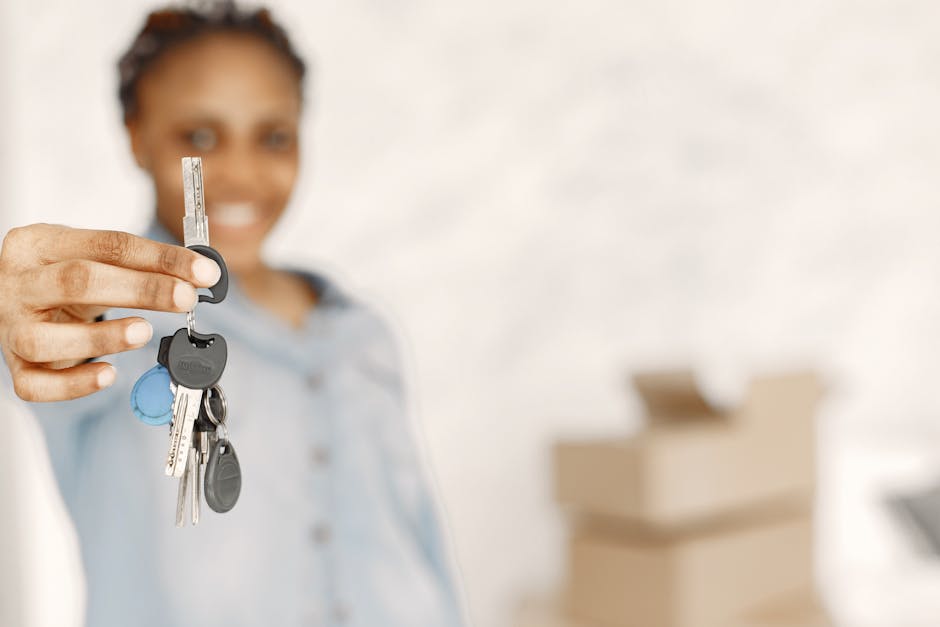 A woman with a blurred background holding a set of keys extended towards the camera. The keys include multiple standard metal keys attached to a plastic keyring with a blue plastic cap. The woman is s